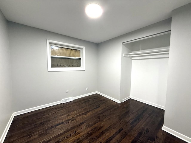 unfurnished bedroom featuring visible vents, baseboards, and dark wood-style flooring