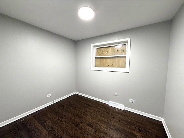 spare room featuring visible vents, baseboards, and dark wood finished floors