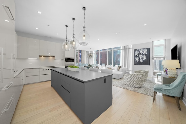 kitchen featuring cooktop, light wood-style floors, open floor plan, modern cabinets, and oven