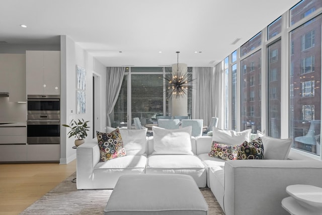 living area featuring light wood-type flooring, visible vents, a notable chandelier, and recessed lighting