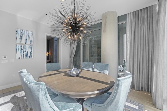 dining space featuring light wood-type flooring, baseboards, and a chandelier