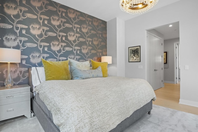 bedroom with a chandelier, recessed lighting, an accent wall, wood finished floors, and baseboards