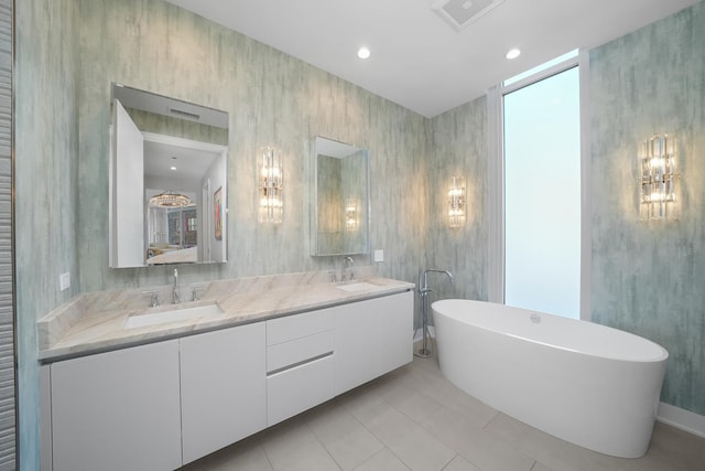 full bath featuring double vanity, a freestanding bath, visible vents, and a sink