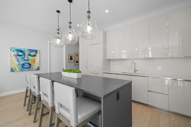 kitchen with light wood-type flooring, modern cabinets, a sink, and a kitchen bar