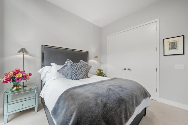 bedroom featuring baseboards, a closet, and light colored carpet