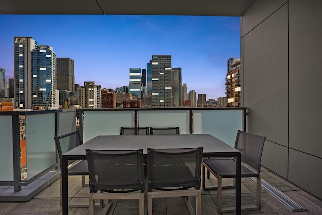 balcony at dusk featuring a city view and outdoor dining space