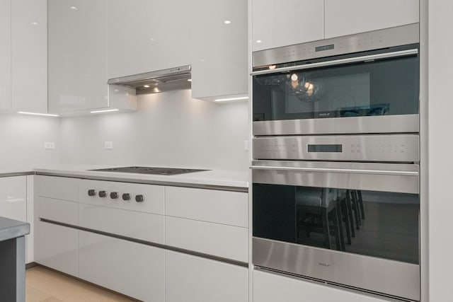 kitchen featuring black electric cooktop, white cabinetry, ventilation hood, and stainless steel double oven