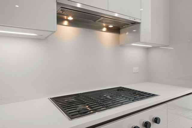 kitchen featuring white cabinets, light countertops, stovetop, and ventilation hood