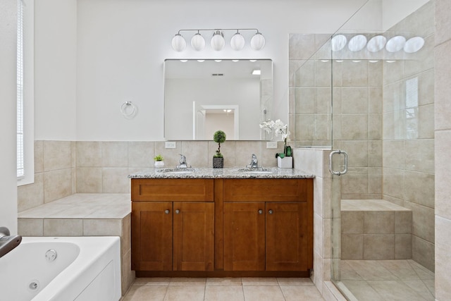 bathroom featuring a shower stall, a tub with jets, double vanity, and a sink