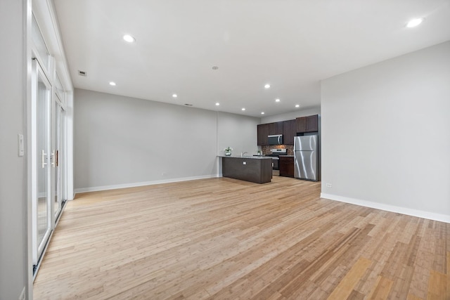 unfurnished living room with light wood-style flooring, recessed lighting, and baseboards