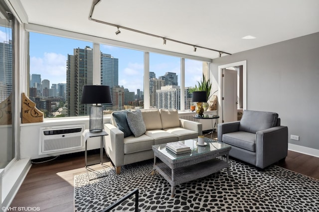 living area with a view of city, a wall unit AC, track lighting, and wood finished floors