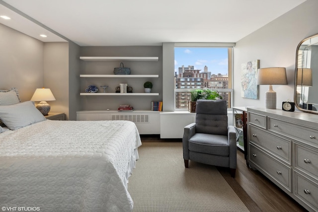 bedroom with dark wood-style flooring and a city view