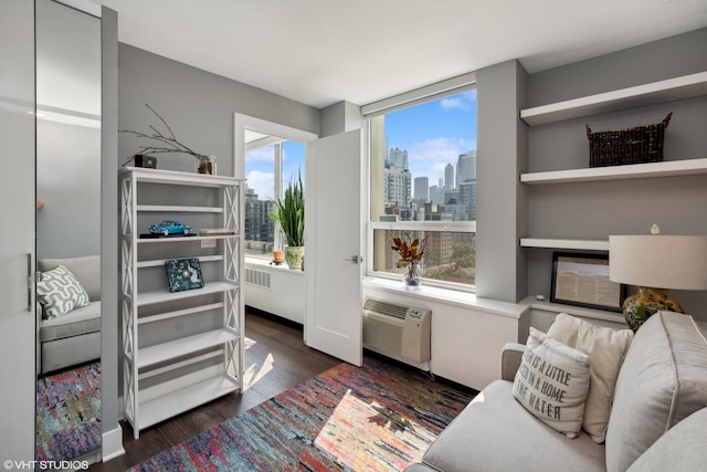 sitting room with a wall unit AC, dark wood-style flooring, and a city view