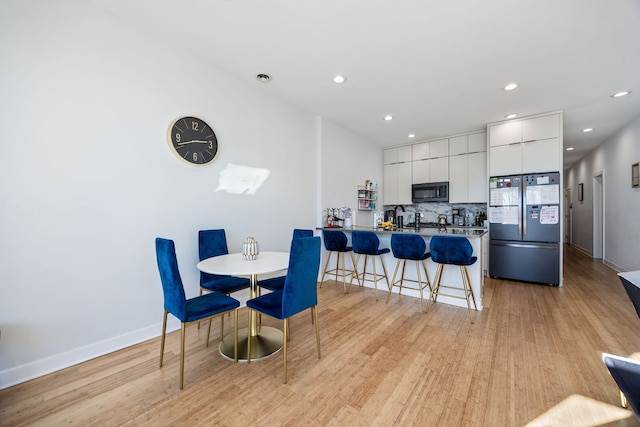 dining area with light wood-style flooring, recessed lighting, and baseboards