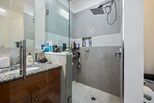 full bathroom featuring a tile shower and vanity