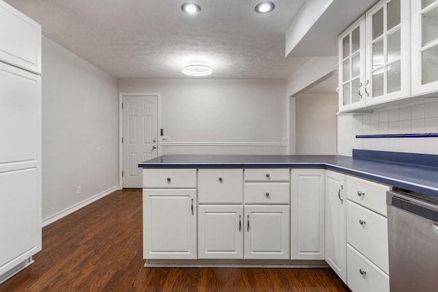 kitchen featuring a peninsula, dark countertops, dark wood-style floors, and stainless steel dishwasher