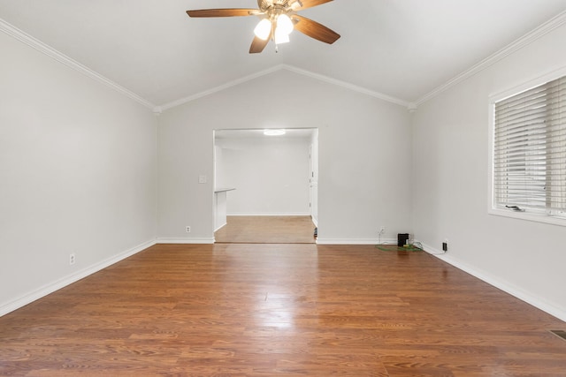 empty room featuring ceiling fan, wood finished floors, baseboards, vaulted ceiling, and ornamental molding