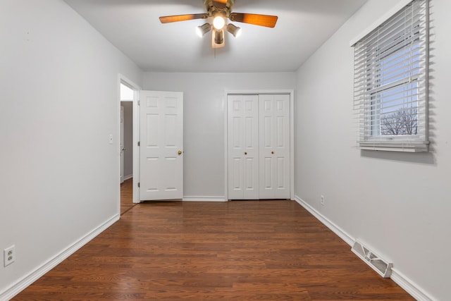 unfurnished bedroom featuring dark wood-style floors, a closet, visible vents, and baseboards