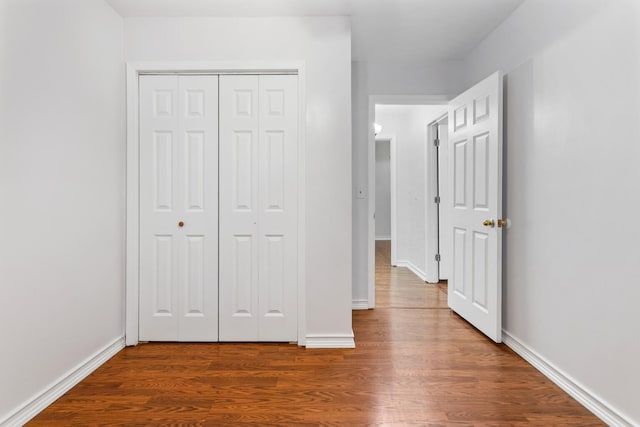 hall with baseboards and wood finished floors