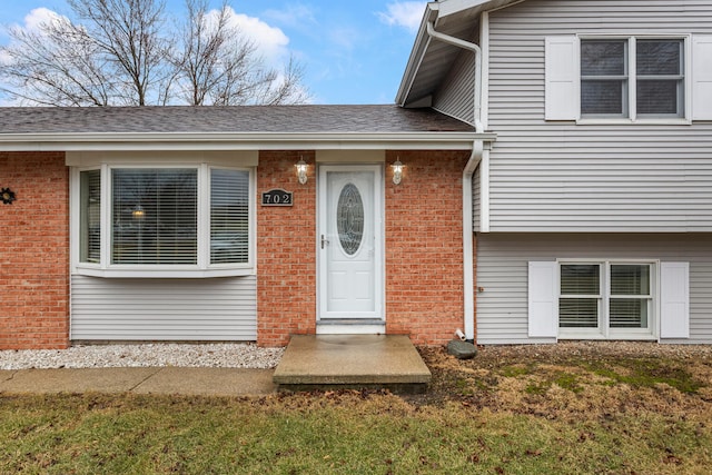 entrance to property featuring brick siding and roof with shingles