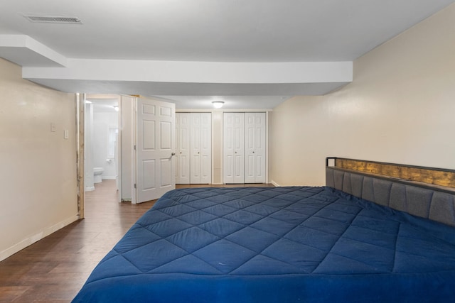 bedroom featuring multiple closets, visible vents, baseboards, and wood finished floors