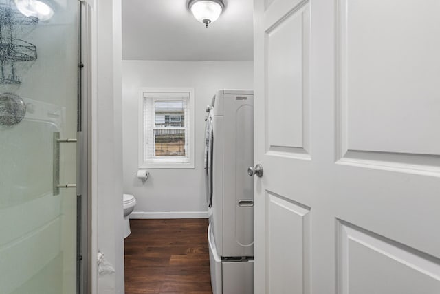 bathroom featuring washer / clothes dryer, toilet, a stall shower, wood finished floors, and baseboards