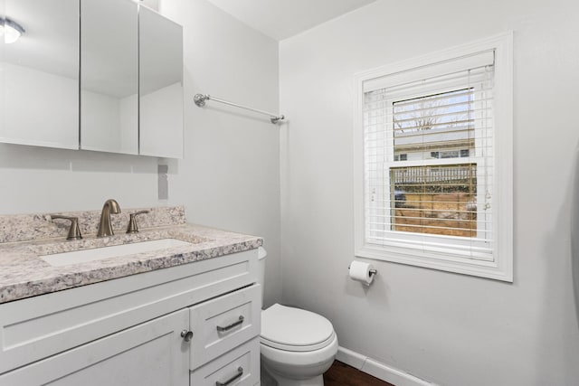 bathroom featuring toilet, vanity, and baseboards