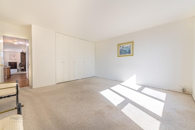 unfurnished bedroom featuring a closet and light colored carpet