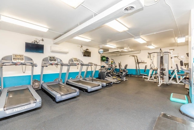 exercise room featuring visible vents and a wall mounted AC