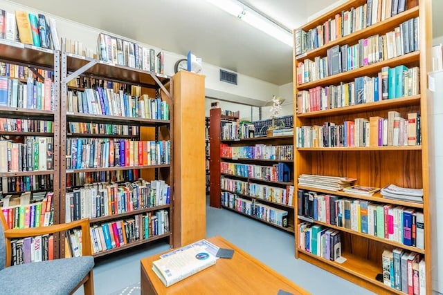 sitting room with wall of books and visible vents