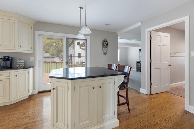 kitchen featuring light wood-style floors, dark countertops, a center island, and decorative light fixtures