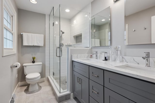 bathroom with a sink, a shower stall, toilet, and double vanity