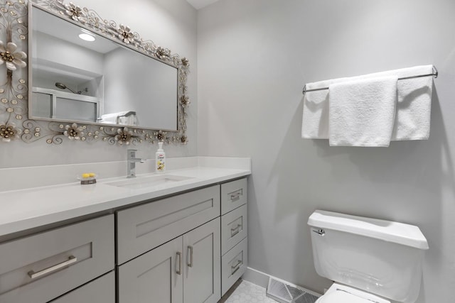 bathroom featuring toilet, vanity, visible vents, and baseboards