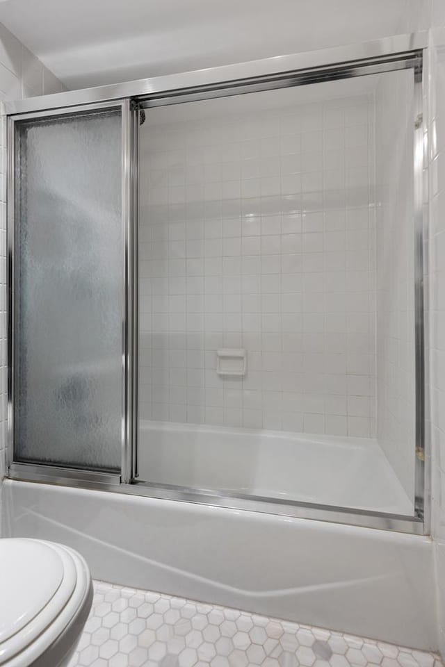 full bathroom featuring bath / shower combo with glass door and toilet