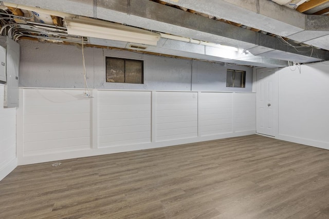 finished basement featuring electric panel and wood finished floors