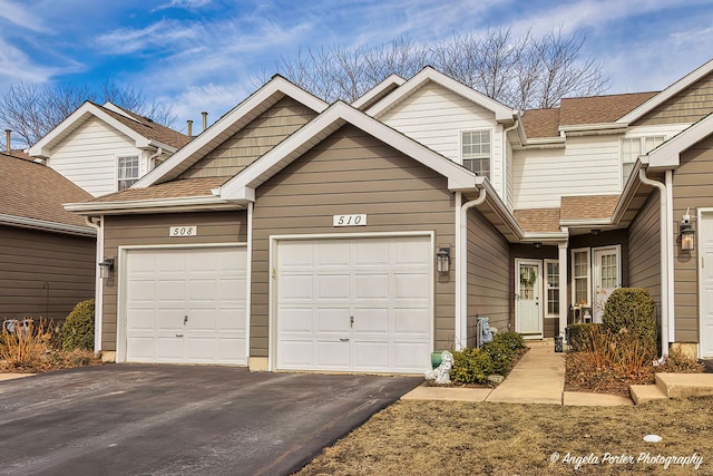 view of front of house featuring a garage, driveway, and a shingled roof