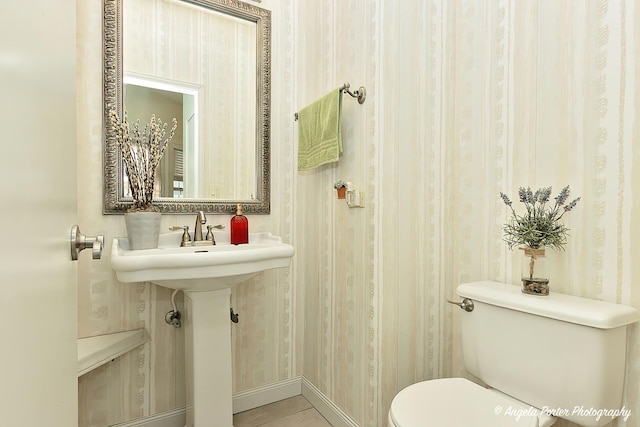 bathroom with baseboards, toilet, and wallpapered walls