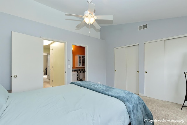 bedroom featuring connected bathroom, carpet flooring, a ceiling fan, visible vents, and multiple closets