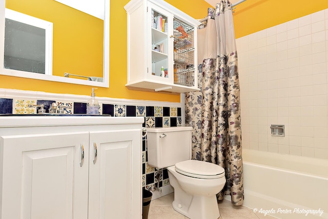 full bath featuring toilet, a wainscoted wall, tile patterned flooring, shower / bathtub combination with curtain, and vanity