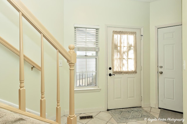 entryway with stairs, light tile patterned floors, visible vents, and baseboards