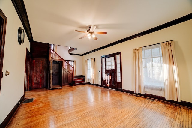 unfurnished living room with stairs, baseboards, light wood-style flooring, and crown molding