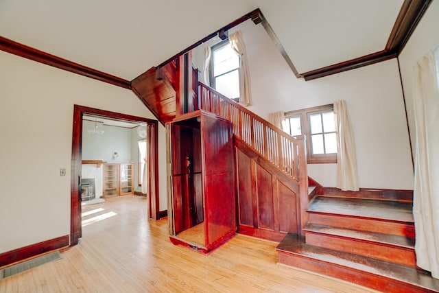 stairs with baseboards, visible vents, crown molding, and wood finished floors