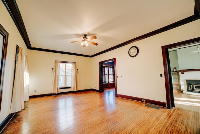 unfurnished room with ornamental molding, light wood-type flooring, baseboards, and a ceiling fan