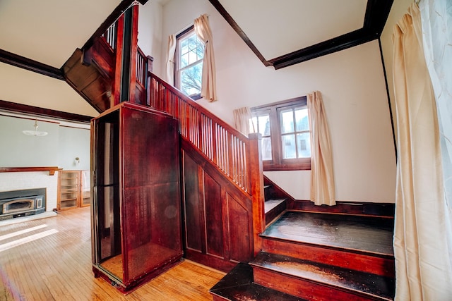 stairway featuring ornamental molding, a fireplace, and hardwood / wood-style floors