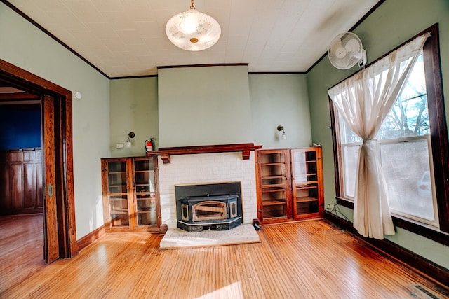 unfurnished living room featuring visible vents, hardwood / wood-style floors, ornamental molding, a wood stove, and baseboards