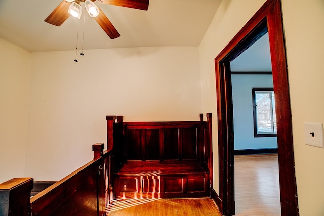 staircase featuring a ceiling fan, baseboards, and wood finished floors