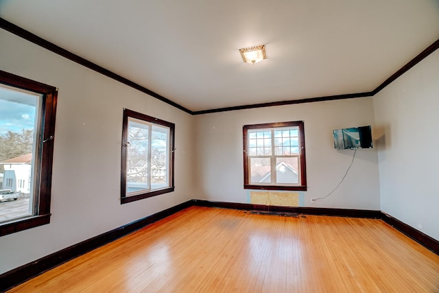 unfurnished room featuring light wood-type flooring, baseboards, and crown molding