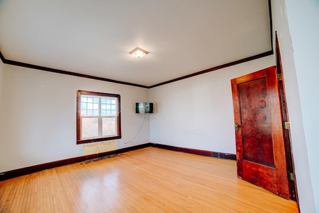 unfurnished room featuring baseboards, light wood-type flooring, and crown molding