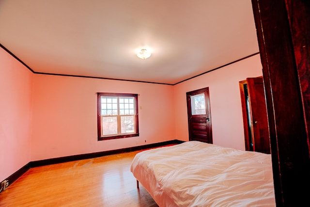 bedroom with multiple windows, wood finished floors, and crown molding