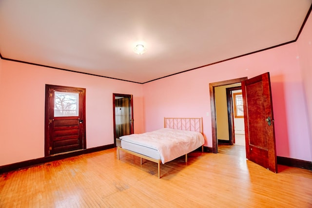 bedroom with light wood finished floors, multiple windows, baseboards, and crown molding